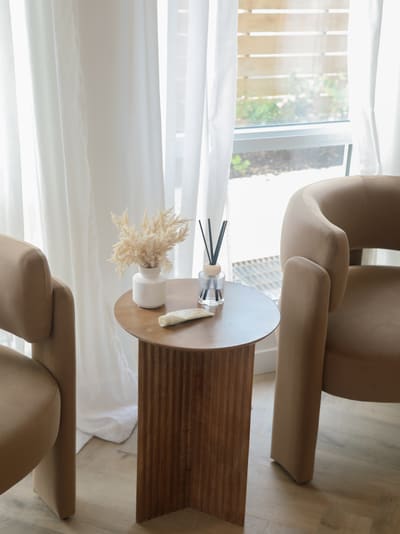 The waiting area at Vella — two soft taupe chairs beside a window